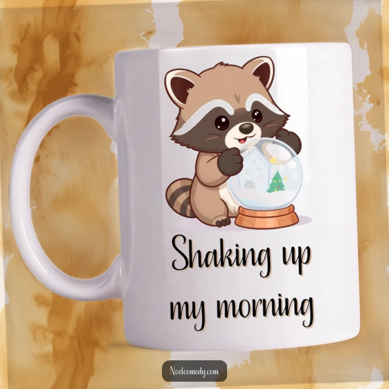 Funny mug shows a curious raccoon in mittens excitedly shaking a snow globe, embodying winter mischief.