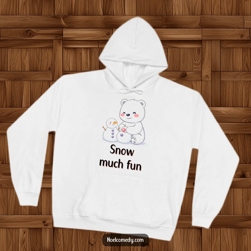 Funny hoodie depicting a happy polar bear building a small snowman with sparkly buttons, perfect for cozy winter laughs.