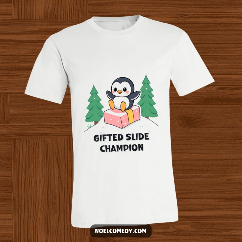 Funny t-shirt depicting a cheerful penguin in mid-slide down a snow-covered hill, using a gift box as a makeshift sled.